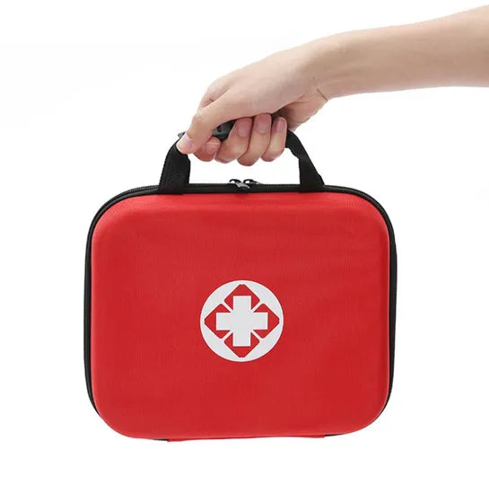 Red first aid kit with a white cross symbol held by a hand on a white background